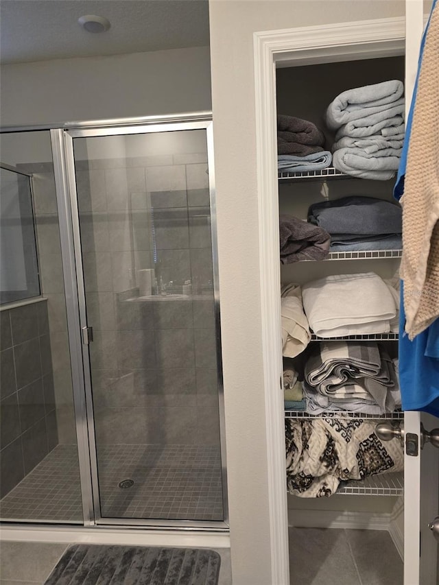 bathroom featuring a stall shower, a spacious closet, and tile patterned floors