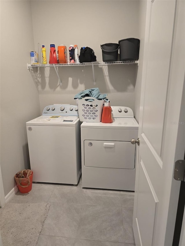 washroom with baseboards, laundry area, light tile patterned flooring, and washer and dryer