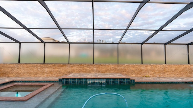 view of pool featuring glass enclosure and an in ground hot tub