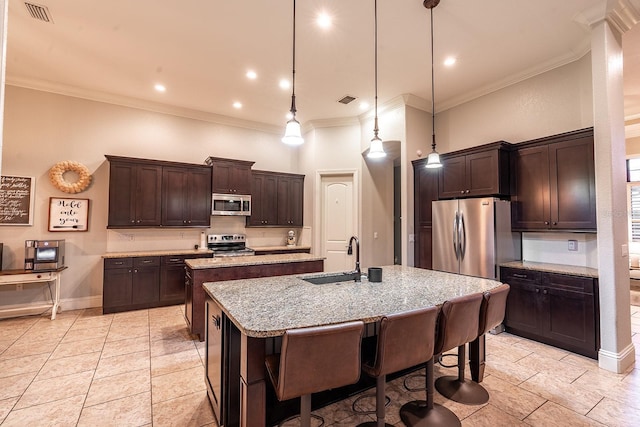 kitchen featuring crown molding, stainless steel appliances, decorative light fixtures, dark brown cabinets, and an island with sink