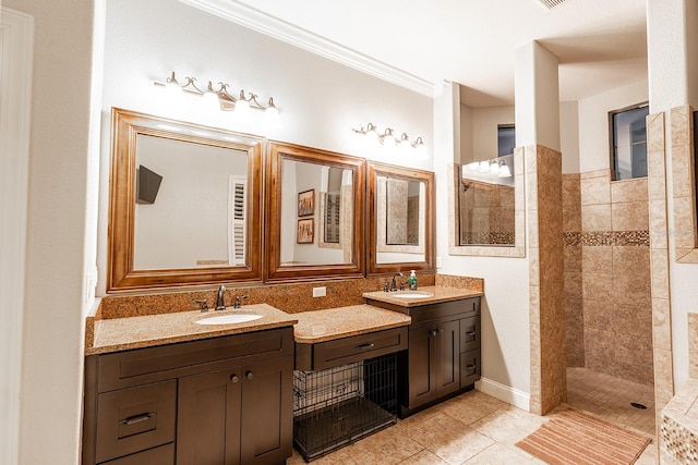 bathroom with ornamental molding, tile patterned flooring, vanity, and a tile shower