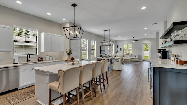 kitchen featuring white cabinets, a breakfast bar, dishwasher, light hardwood / wood-style floors, and sink