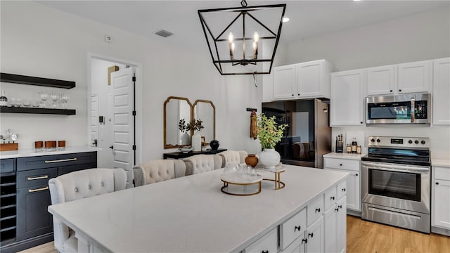 kitchen with a center island, stainless steel appliances, decorative light fixtures, and white cabinets