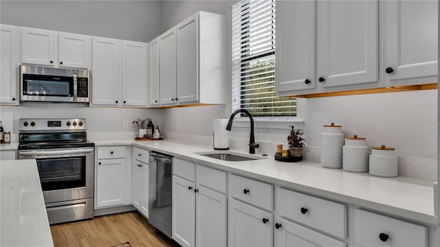 kitchen with light hardwood / wood-style flooring, appliances with stainless steel finishes, sink, and white cabinets