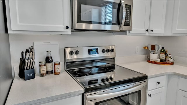 kitchen featuring white cabinets, stainless steel appliances, and light stone counters