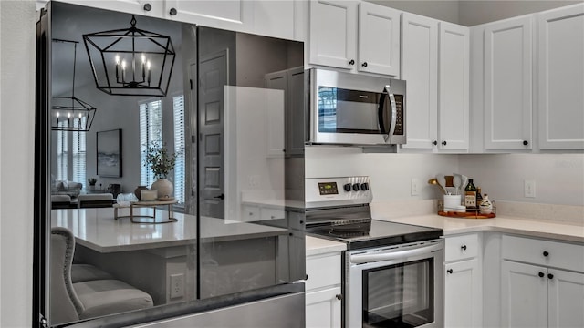 kitchen featuring white cabinetry, stainless steel appliances, an inviting chandelier, and hanging light fixtures