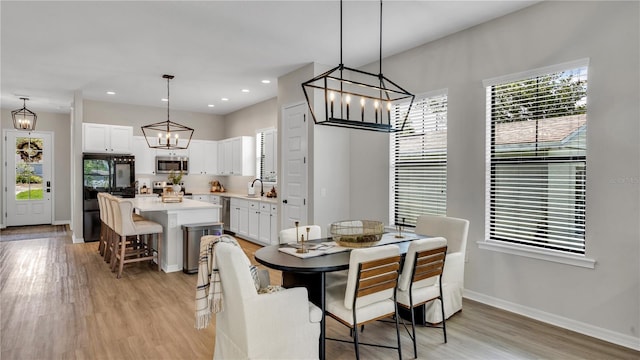 dining space featuring sink, a healthy amount of sunlight, and light hardwood / wood-style flooring