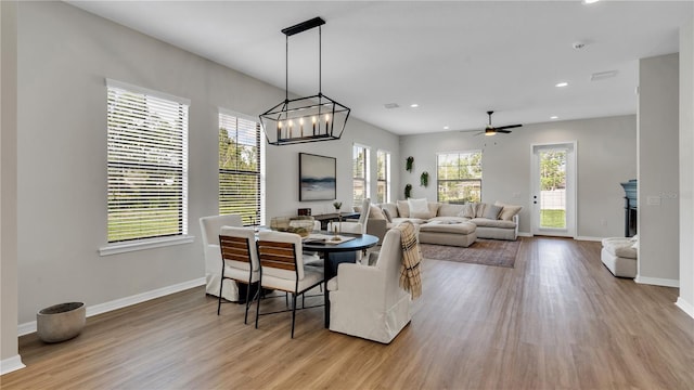 dining room featuring ceiling fan with notable chandelier, light wood-type flooring, and a wealth of natural light