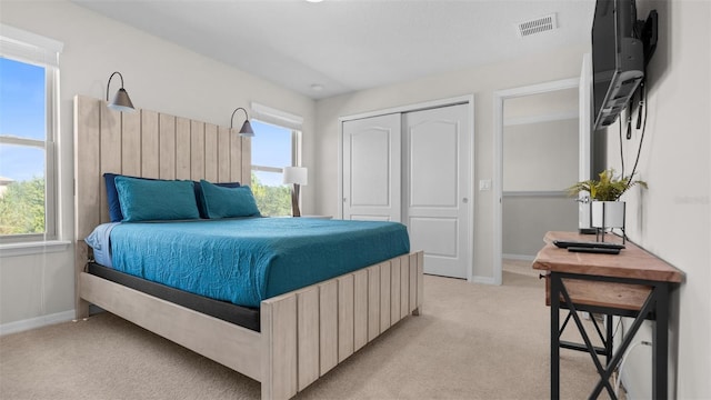 bedroom featuring a closet, light carpet, and multiple windows