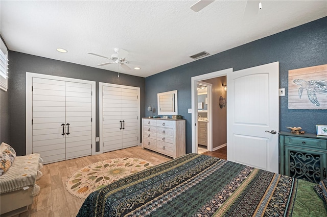 bedroom featuring light wood finished floors, visible vents, a textured ceiling, and connected bathroom
