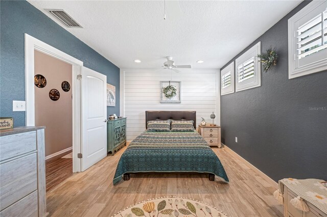 bedroom with a textured ceiling, light hardwood / wood-style floors, and ceiling fan