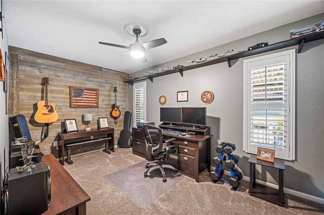 carpeted office space featuring ceiling fan and wooden walls