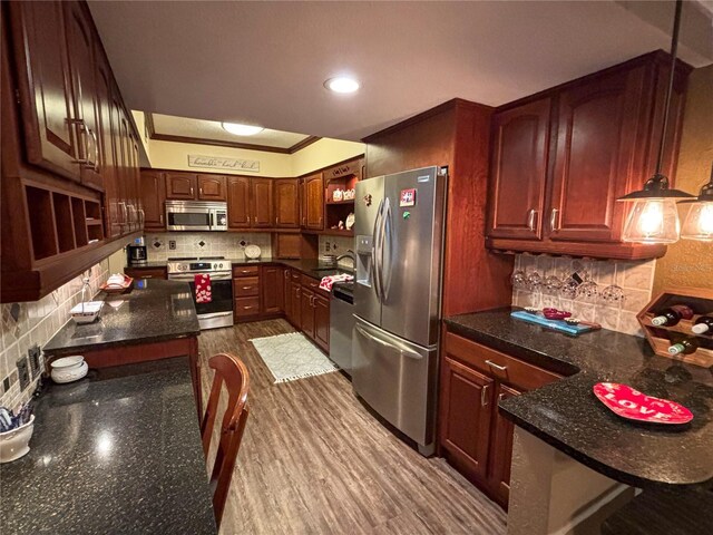 kitchen featuring tasteful backsplash, appliances with stainless steel finishes, pendant lighting, and kitchen peninsula