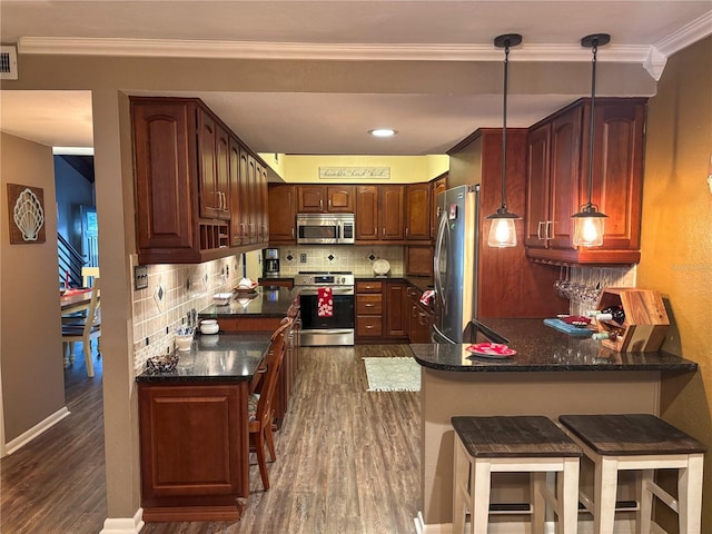 kitchen with a breakfast bar, decorative light fixtures, tasteful backsplash, kitchen peninsula, and stainless steel appliances