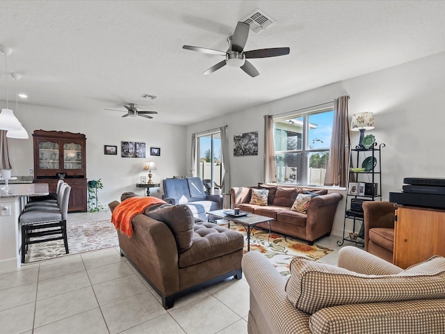 living room featuring ceiling fan, light tile patterned floors, and a textured ceiling