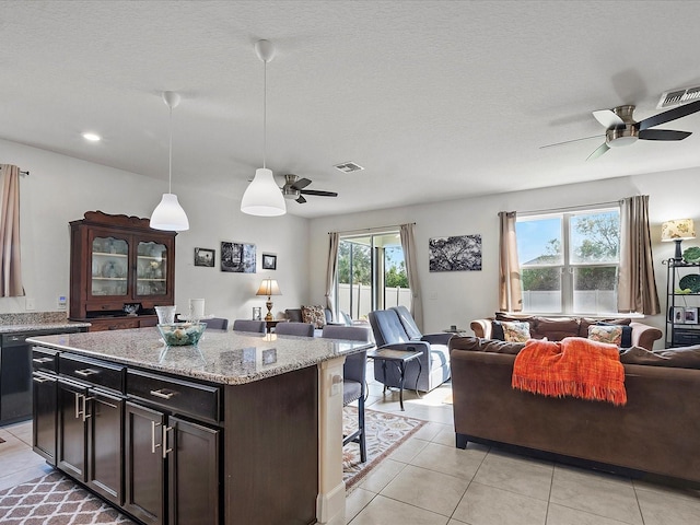 kitchen with pendant lighting, a textured ceiling, a kitchen island, and light tile patterned floors