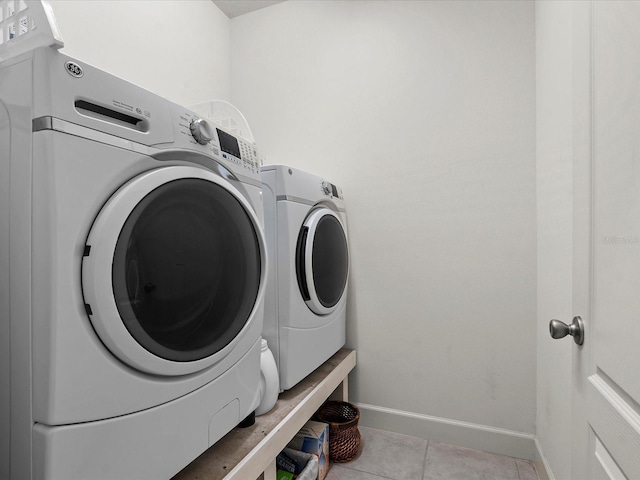 clothes washing area featuring washer and clothes dryer and light tile patterned floors