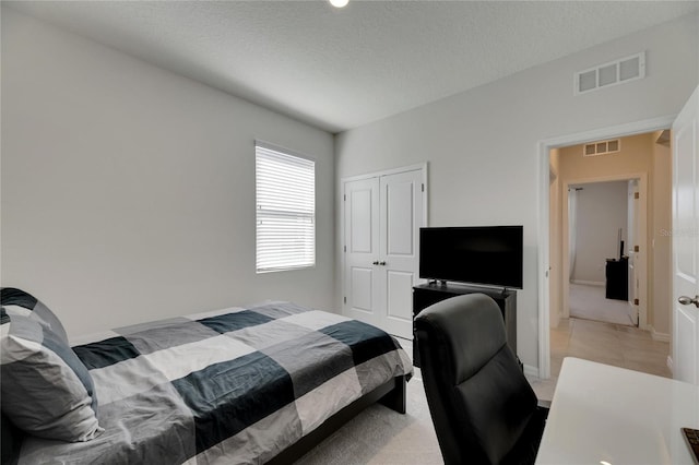 bedroom featuring light carpet, a textured ceiling, and a closet