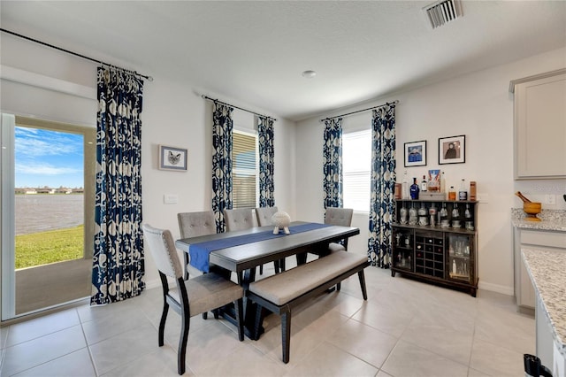 tiled dining space with a water view and a healthy amount of sunlight