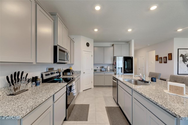 kitchen featuring a center island with sink, light tile patterned floors, stainless steel appliances, and sink