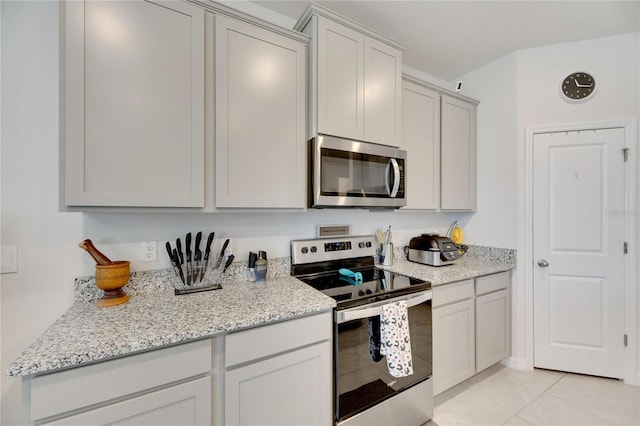 kitchen with light stone countertops, light tile patterned floors, and stainless steel appliances