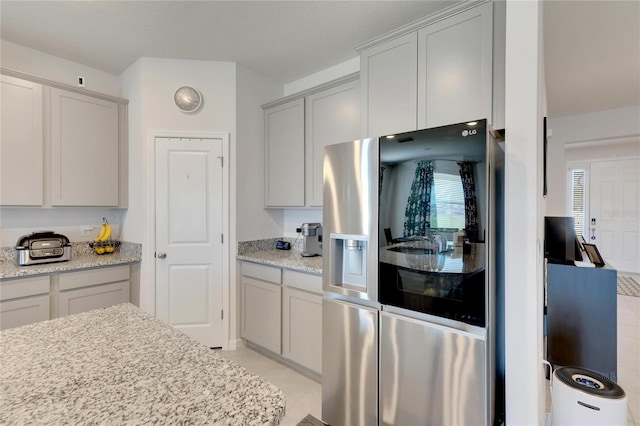 kitchen featuring light stone countertops and stainless steel refrigerator with ice dispenser