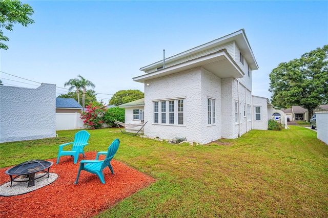 rear view of property featuring a yard, an outdoor fire pit, and a patio