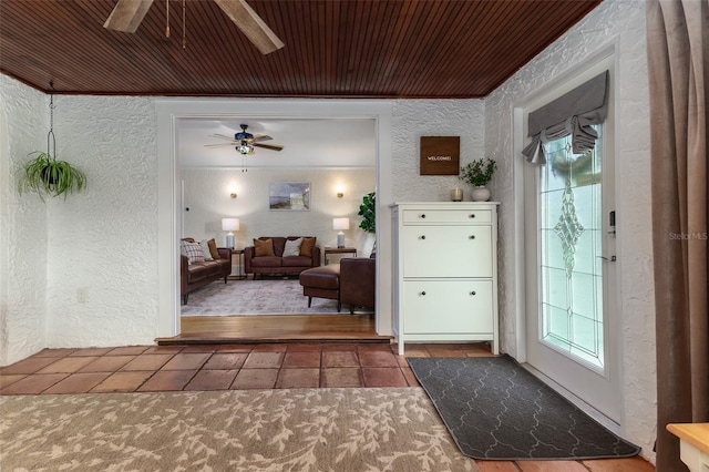 entrance foyer featuring crown molding, tile patterned floors, wood ceiling, and ceiling fan