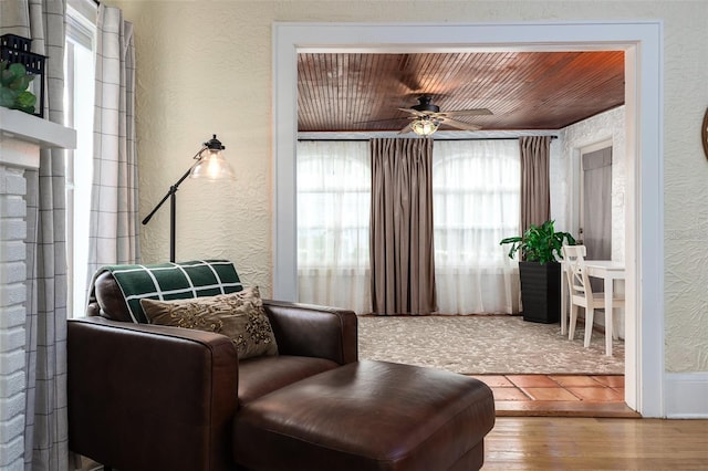 living area with hardwood / wood-style floors, wooden ceiling, and ceiling fan