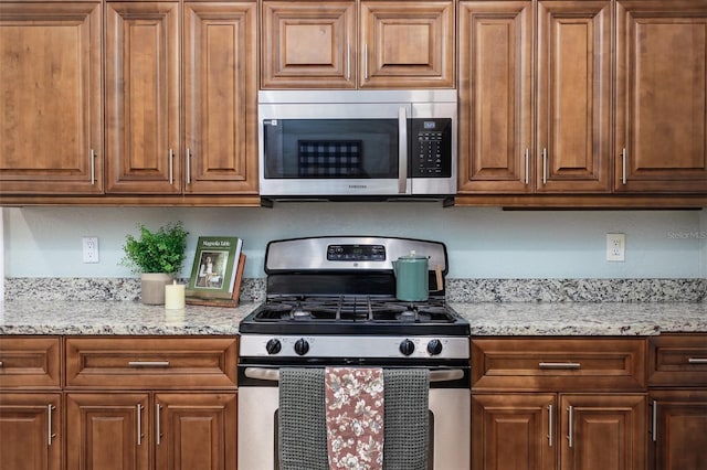 1806 17th St NW, Winter Haven, FL 33881 - kitchen featuring stainless steel appliances, light stone countertops, and brown cabinetry