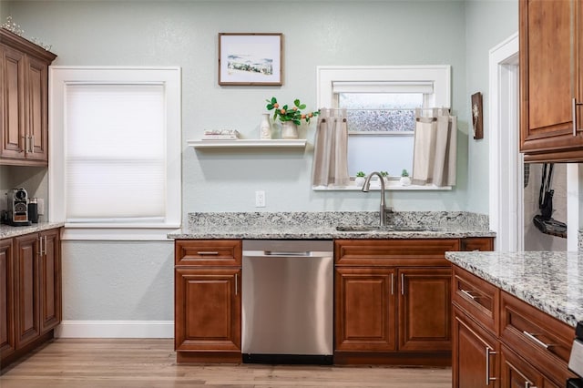 kitchen with light hardwood / wood-style floors, light stone countertops, stainless steel dishwasher, and sink