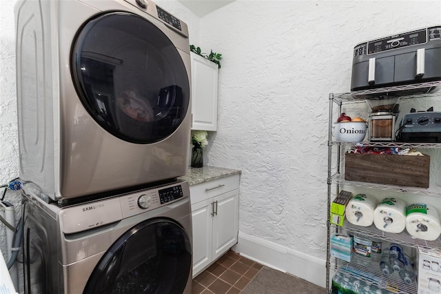 1806 17th St NW, Winter Haven, FL 33881 - laundry area with stacked washer / drying machine, baseboards, cabinet space, dark tile patterned flooring, and a textured wall