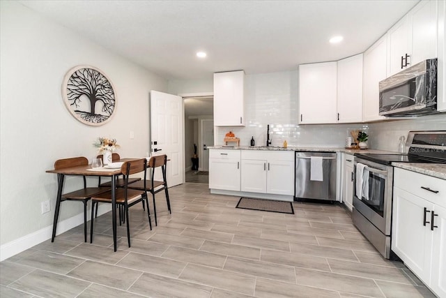 kitchen featuring white cabinets, tasteful backsplash, light stone countertops, sink, and stainless steel appliances