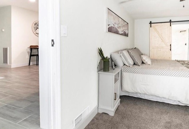 bedroom featuring a barn door and light carpet