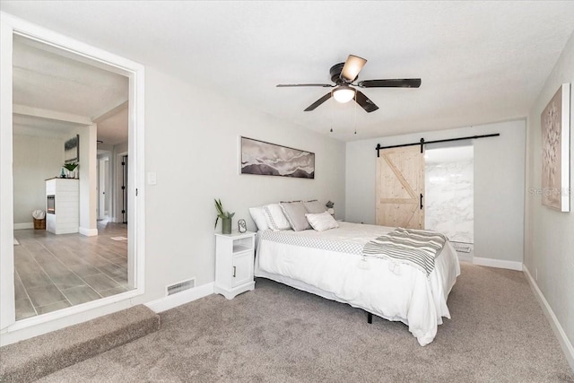 bedroom with a barn door, carpet flooring, and ceiling fan