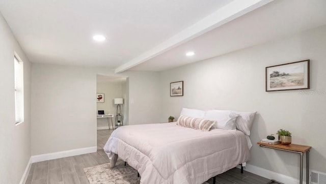 bedroom with beam ceiling and light hardwood / wood-style floors