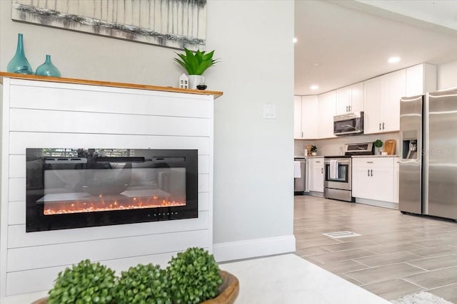 kitchen with appliances with stainless steel finishes, hardwood / wood-style floors, and white cabinets