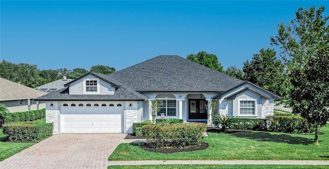300 Winona Ct, Auburndale, FL 33823 - view of front of home with stone siding, decorative driveway, a front lawn, a garage, and roof with shingles