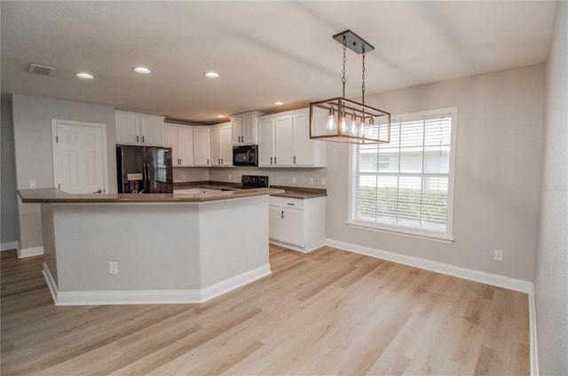 kitchen featuring hanging light fixtures, black appliances, a center island, light wood-type flooring, and white cabinets