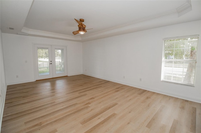 empty room featuring french doors, a raised ceiling, and light hardwood / wood-style flooring