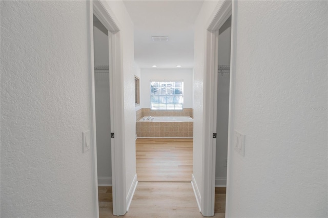 hallway with light hardwood / wood-style floors