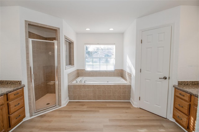 bathroom featuring vanity, plus walk in shower, and wood-type flooring