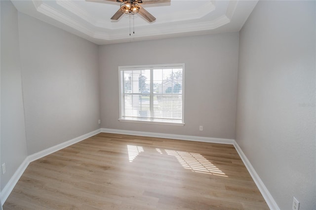 unfurnished room featuring light hardwood / wood-style floors, crown molding, a tray ceiling, and ceiling fan