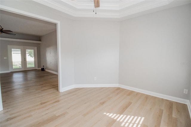 empty room with french doors, crown molding, light wood-type flooring, and ceiling fan