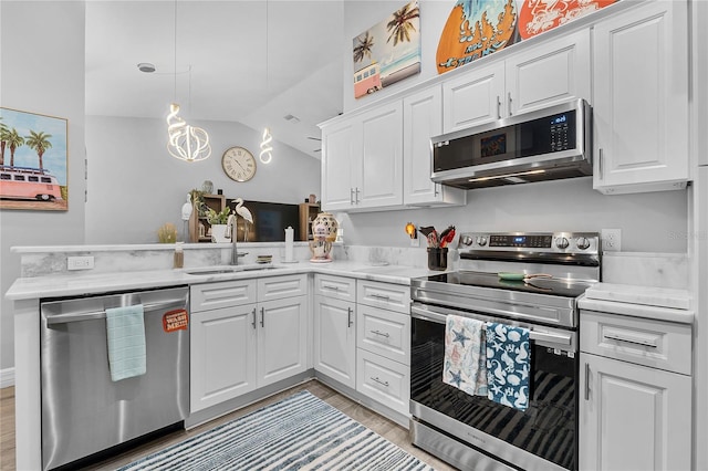 kitchen featuring vaulted ceiling, appliances with stainless steel finishes, and white cabinetry