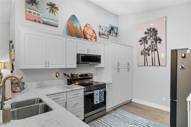 kitchen featuring sink, white cabinetry, stainless steel appliances, and light hardwood / wood-style floors