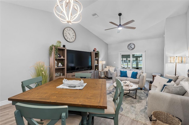 living room with vaulted ceiling, ceiling fan with notable chandelier, and light hardwood / wood-style floors