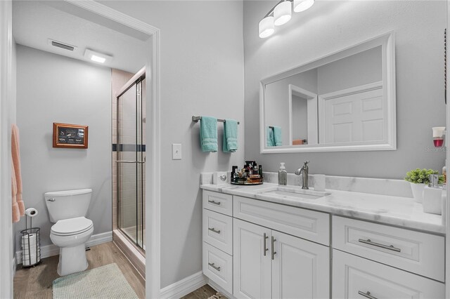 bathroom with vanity, hardwood / wood-style floors, a shower with shower door, and toilet