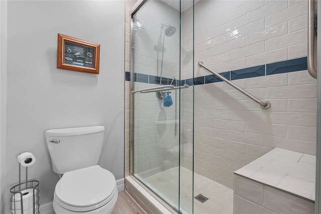 bathroom featuring a shower with shower door, wood-type flooring, and toilet