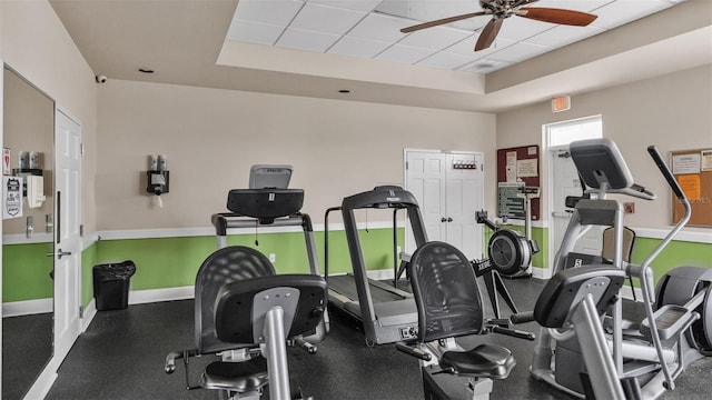 workout area featuring a drop ceiling, a raised ceiling, and ceiling fan